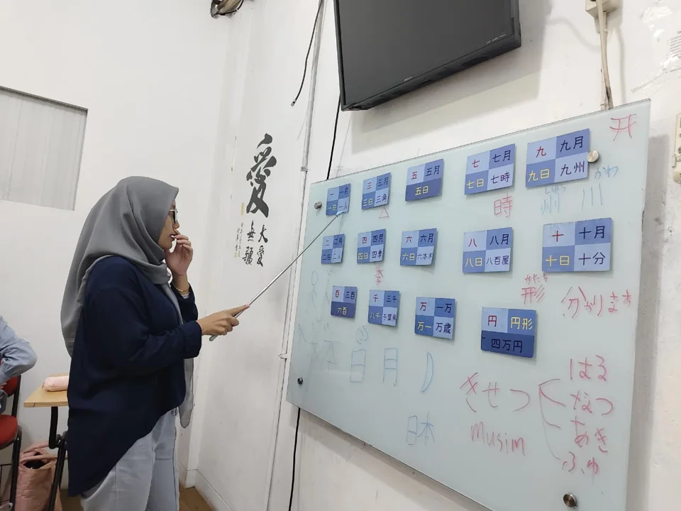Siswa berlatih membaca kanji dengan kartu di papan tulis